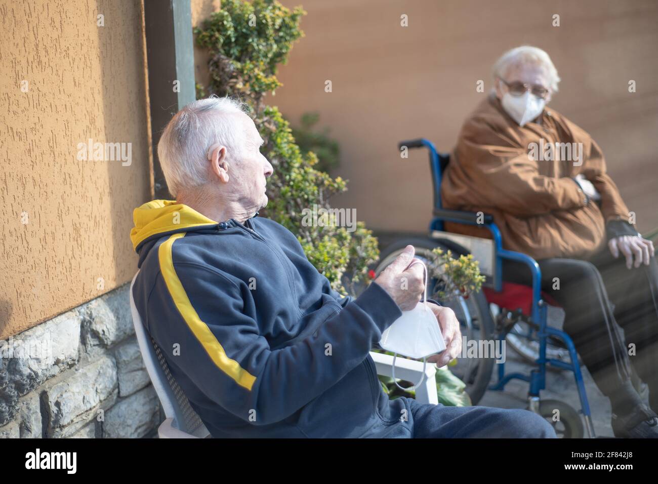 Uomo anziano e donna in attesa all'aperto per ricevere il vaccino Covid-19, pensando a possibili effetti collaterali. Foto Stock