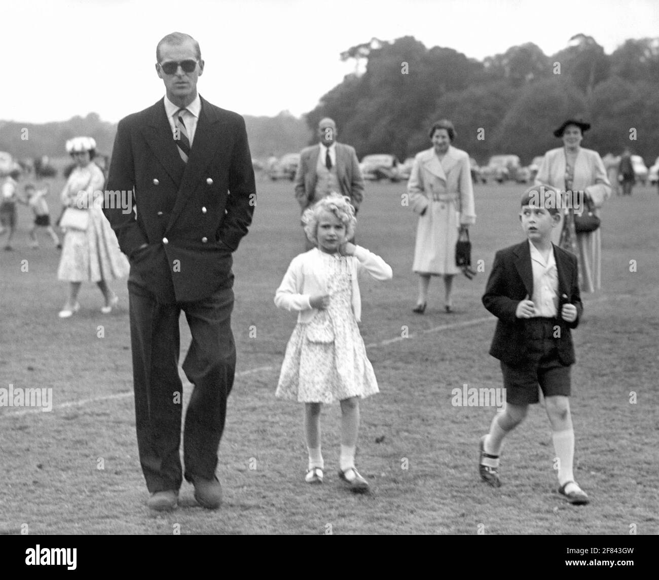 SOLO IN BIANCO E NERO Foto del 20/06/56 della Principessa reale che adegua il suo cardigan mentre suo fratello, il Principe di Galles, guarda il Duca di Edimburgo a Smith's Lawn, Windsor Great Park, dove stavano guardando il Polo. La Principessa reale ha reso omaggio a suo padre, descrivendolo come 'il mio insegnante, il mio sostenitore e il mio critico'. Data di emissione: Domenica 11 aprile 2021. In un messaggio pubblicato sul conto Twitter della famiglia reale, Anne ha detto che era l'esempio di suo padre di una 'vita ben vissuta e servizio liberamente dato che ho voluto emulare '. Con il messaggio, ha pubblicato un im Foto Stock