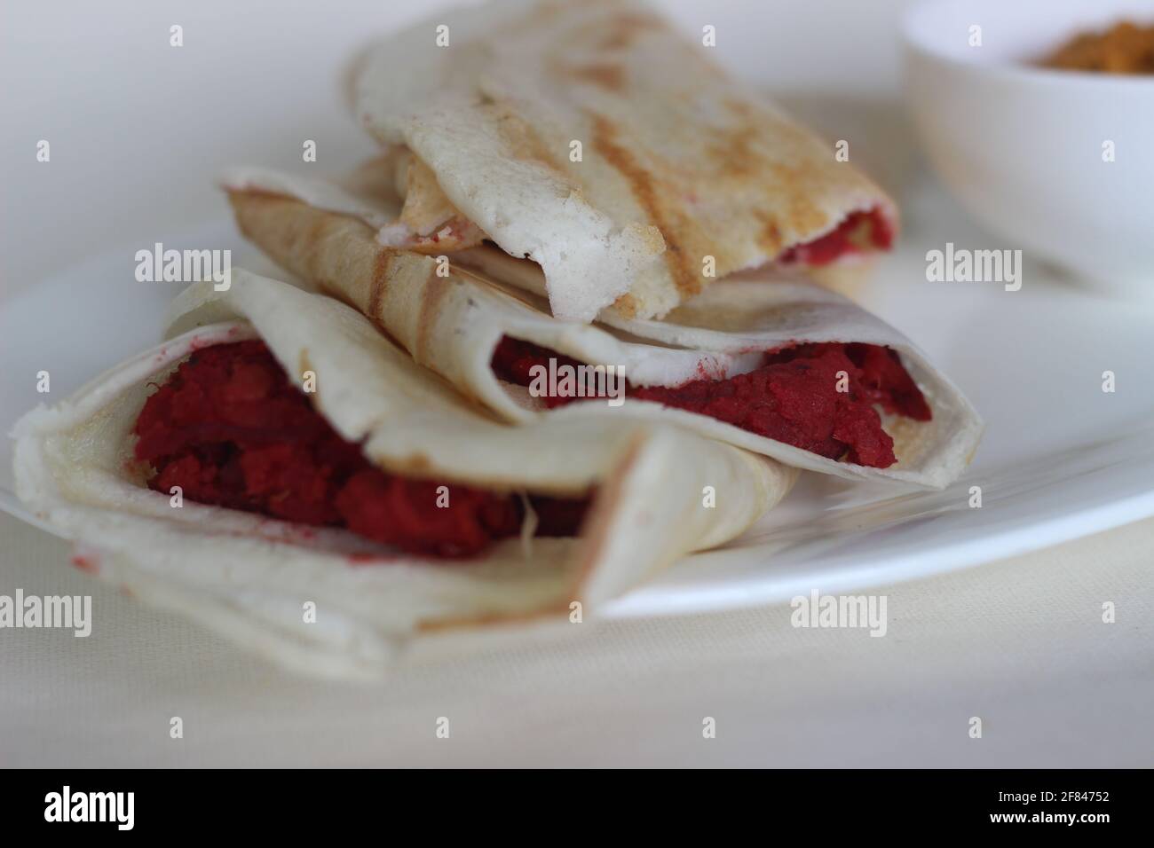 Rotoli DOSA con barbabietola masala all'interno. Localmente conosciuto come masala di barbabietola dosa. Scatto su sfondo bianco Foto Stock