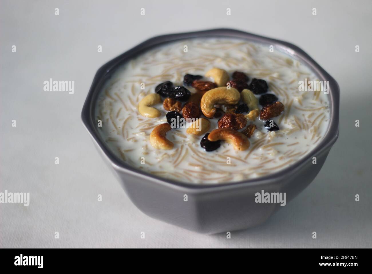 Dolce dell'India del Sud fatto con vermicelli, latte, ghee, zucchero o gelatine, uva passa e noci localmente conosciuto come Semiya payasam. Scatto su sfondo bianco Foto Stock