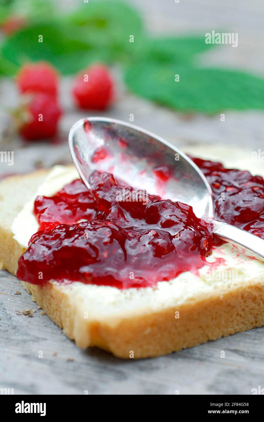 Marmellata di lamponi su pane tostato (Rubus idaeus) , marmellata di lamponi, cucchiaio Foto Stock