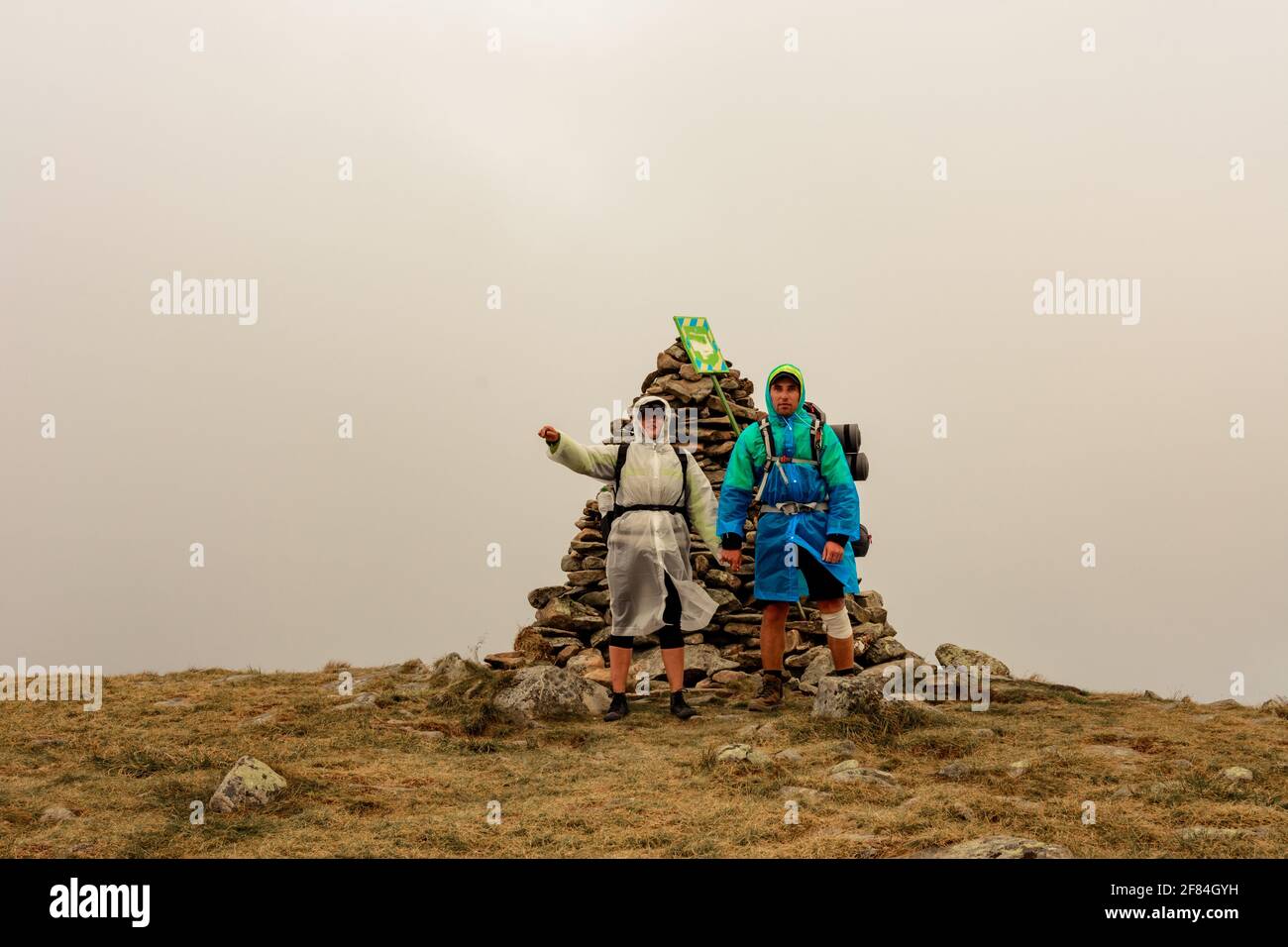 Turisti in impermeabile si trovano sulla cima della montagna, Monte Brebeneskul e nebbia, nuvole di pioggia sulla dorsale montenegrina, turisti felici.2020 Foto Stock