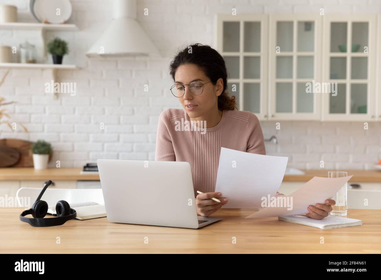 Pensieroso hispanic femmina tenere i documenti finanziari guardare sullo schermo del pc Foto Stock