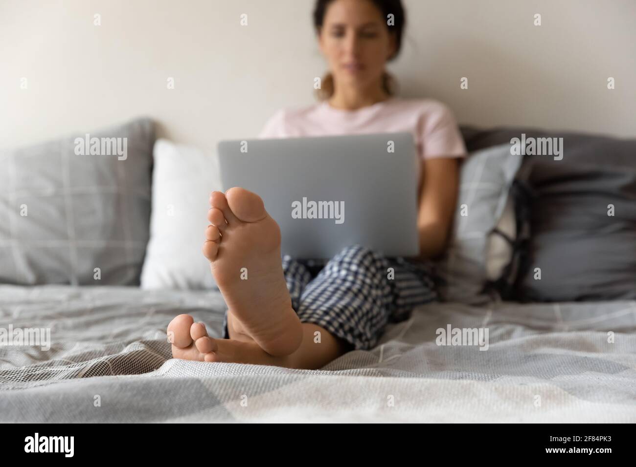 Giovane donna latina relax a piedi nudi con computer portatile su un comodo letto Foto Stock