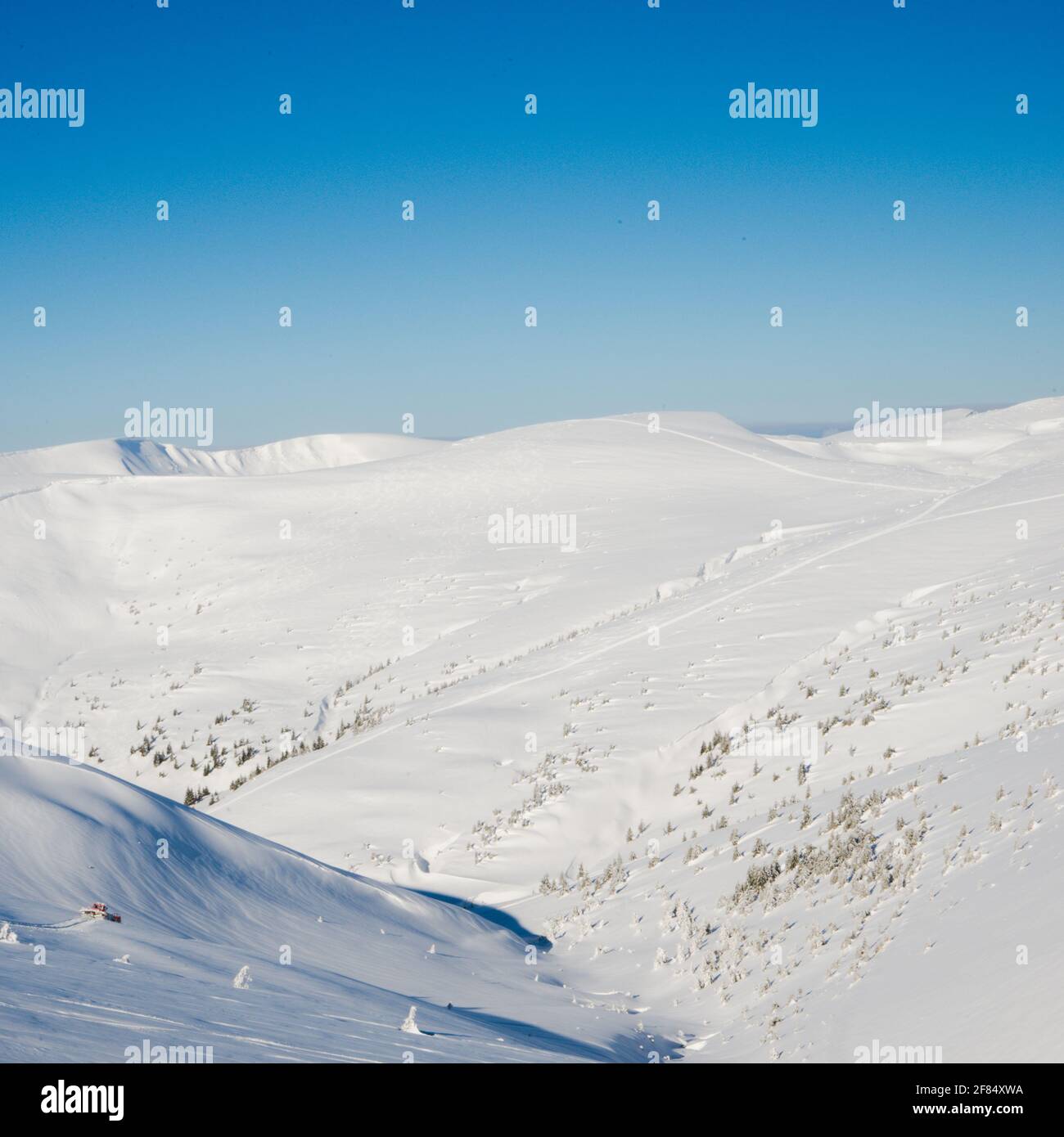 Vista delle vette e delle rocce ricoperte di neve intorno le nuvole sotto il cielo blu Foto Stock