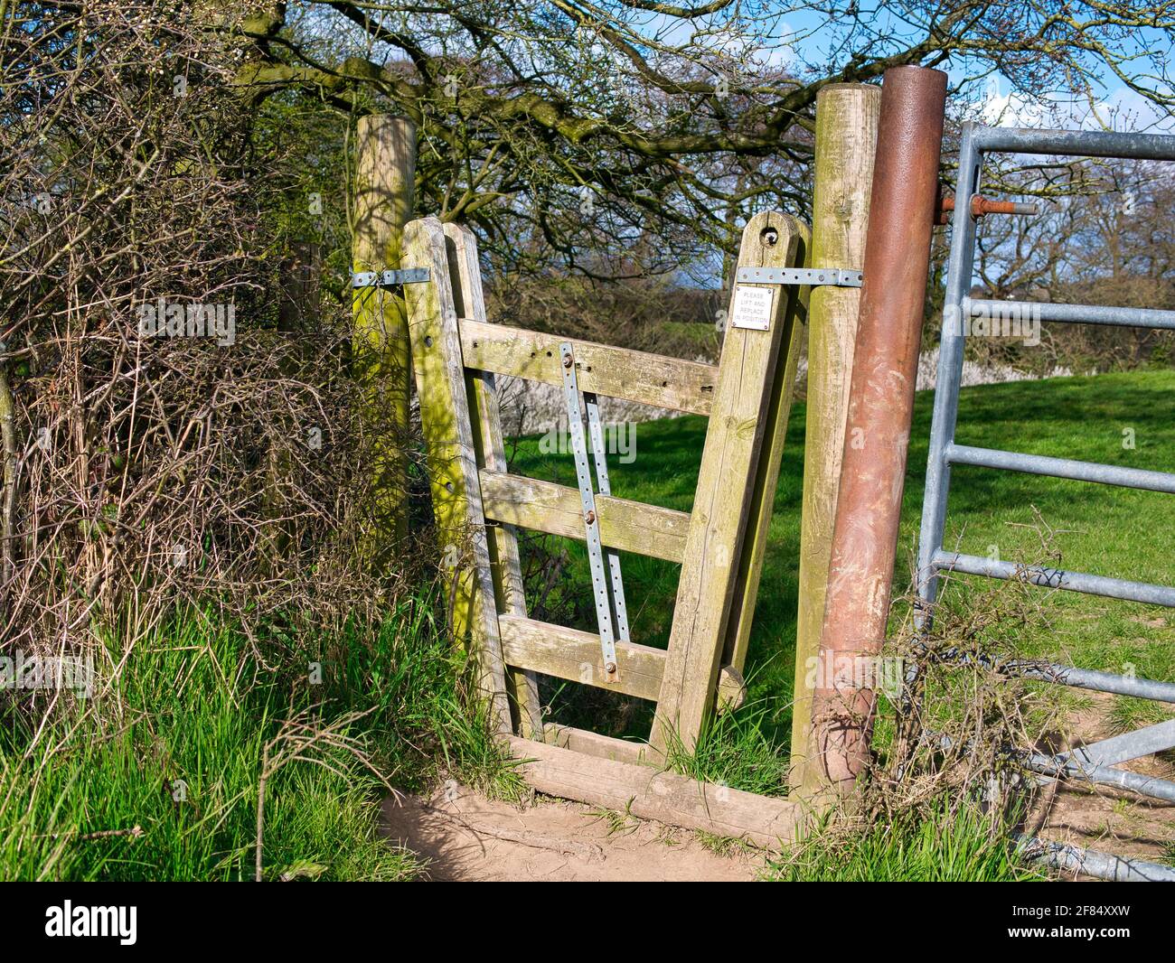 Una porta di concertina si trova tra due campi su un percorso di campagna a piedi. Le tre traverse sono unite da una barra metallica che ne consente il sollevamento Foto Stock