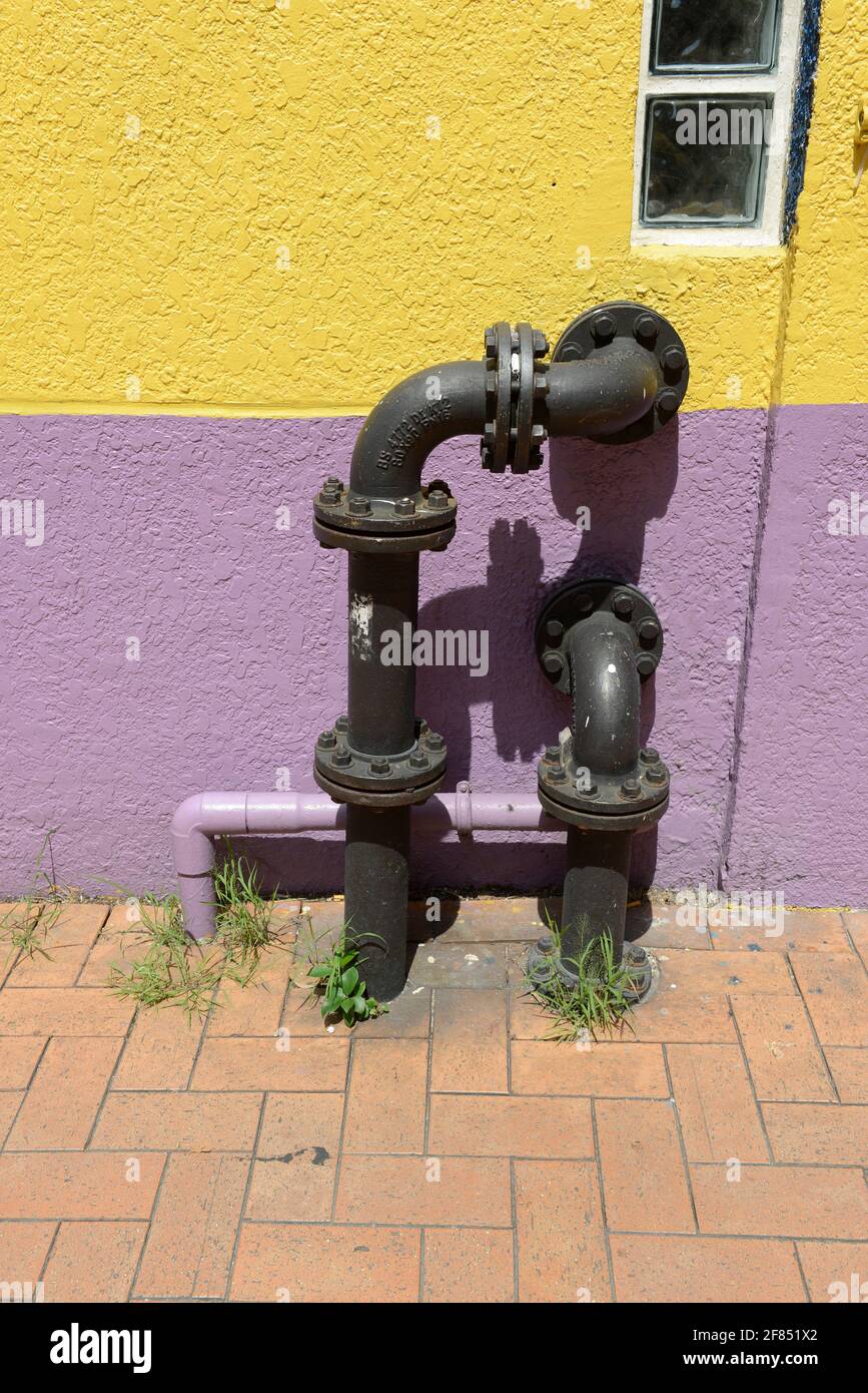 Due tubi neri all'esterno di un edificio colorato su una strada nell'isola di Tsing Yi, Hong Kong, Cina Foto Stock