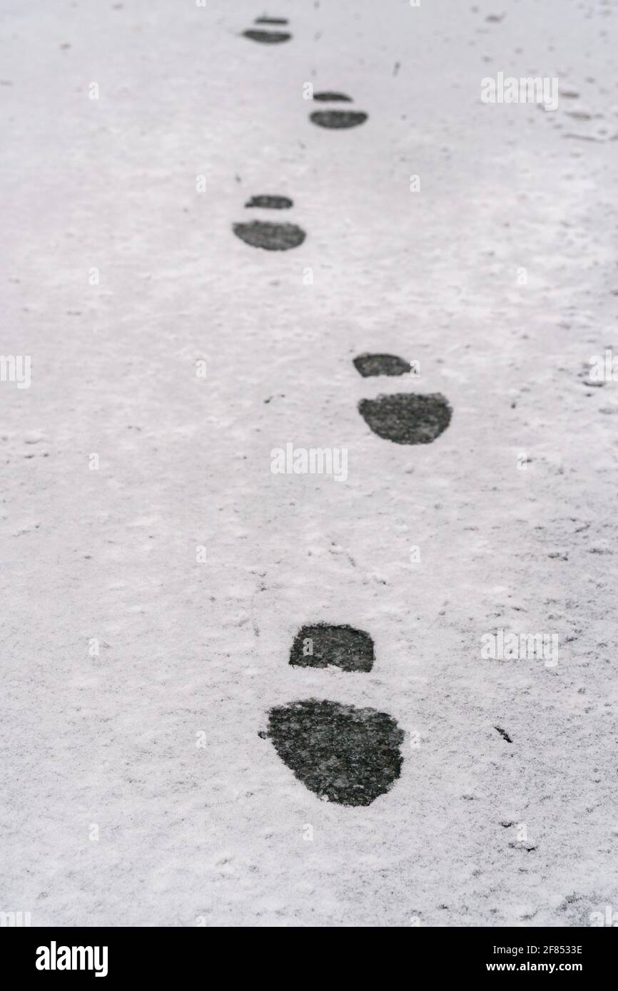 Una sola linea di passi in una leggera polvere di neve. Una persona ha voluto uscire prima di tutti gli altri. Foto Stock
