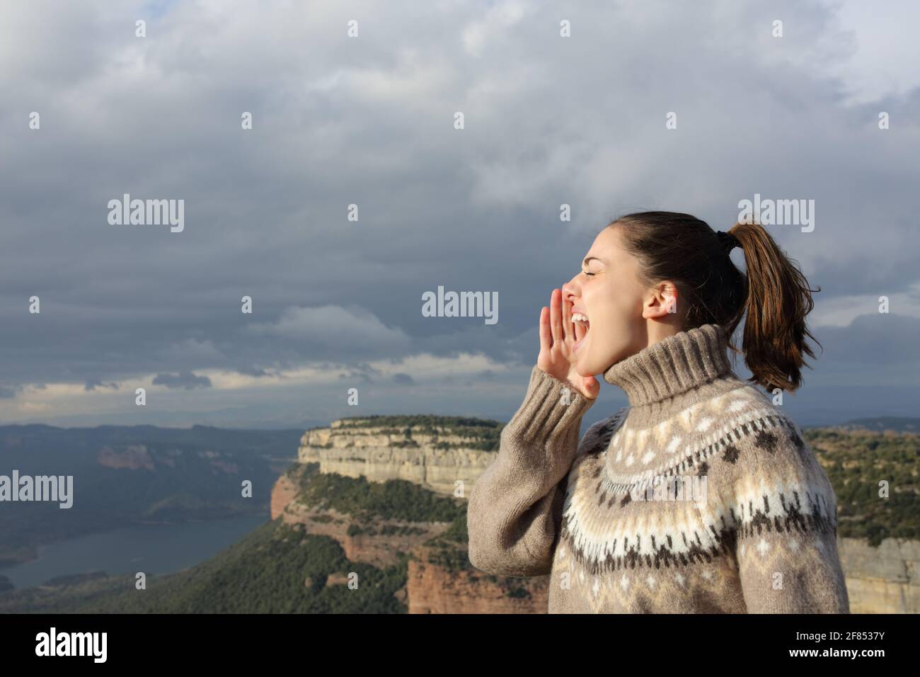 Profilo di una donna che grida in montagna in inverno vacanze Foto Stock