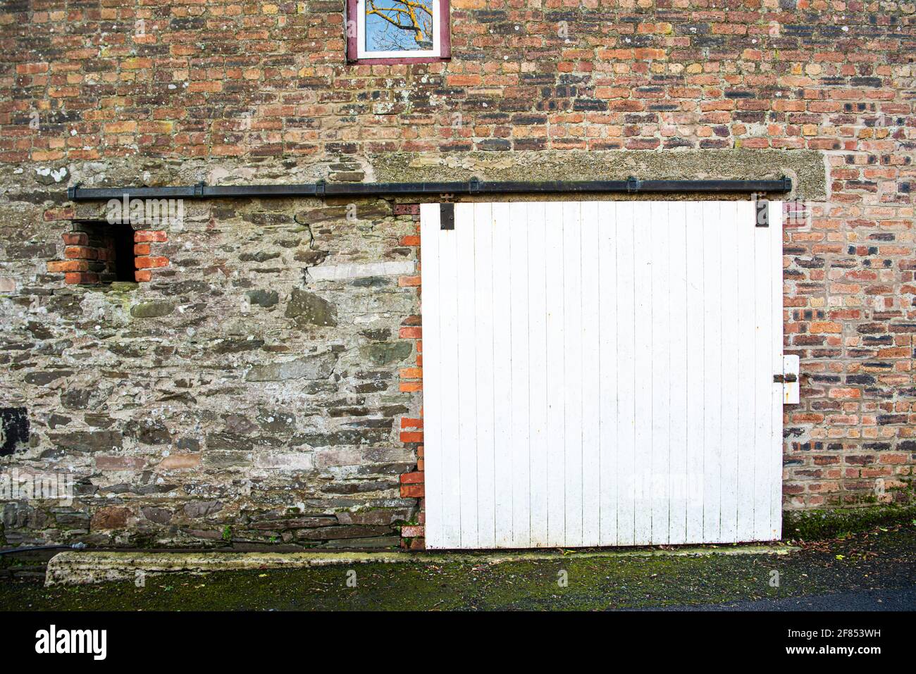 Porta scorrevole in legno su un tradizionale fienile irlandese costruito in mattoni in una vecchia fattoria. Foto Stock