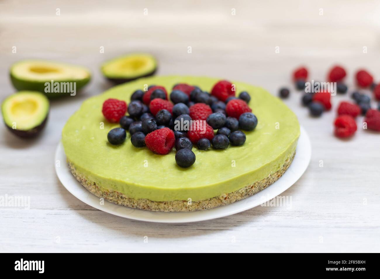 Gustoso avocado fatto in casa e torta al lime cruda con mirtilli e lamponi, ricette vegane sane Foto Stock