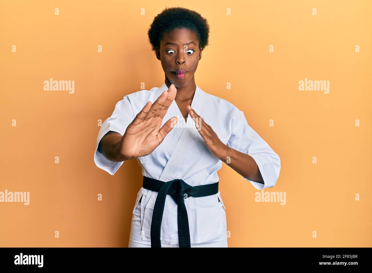 Giovane afroamericana che indossa kimono karate e cintura nera facendo  faccia di pesce con la bocca e gli occhi squinting, pazzo e comico Foto  stock - Alamy