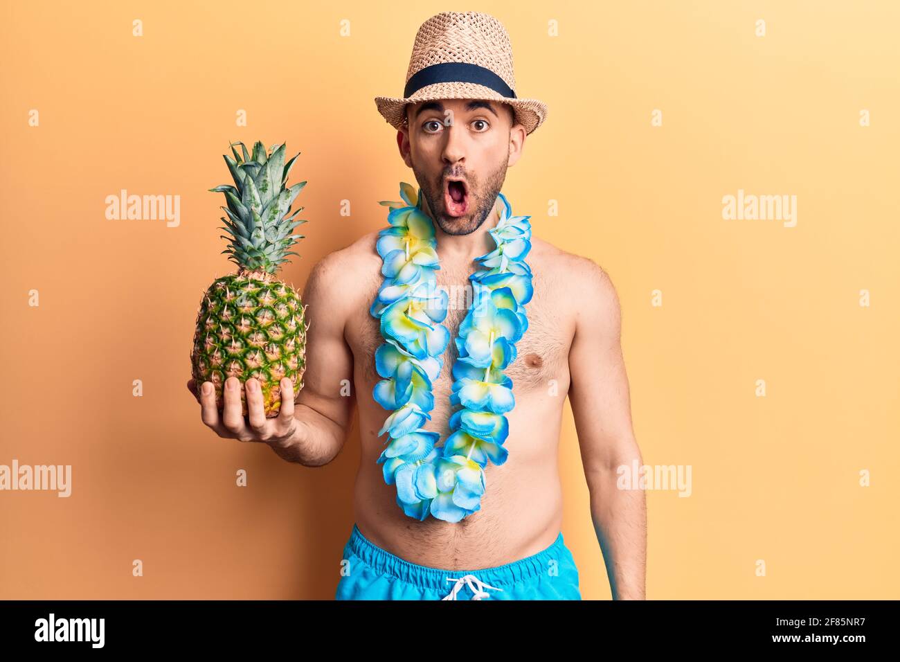 Giovane bell'uomo calvo che indossa costume da bagno e lei hawaiano che  tiene ananas spaventato e stupito con bocca aperta per sorpresa, viso  incredulo Foto stock - Alamy