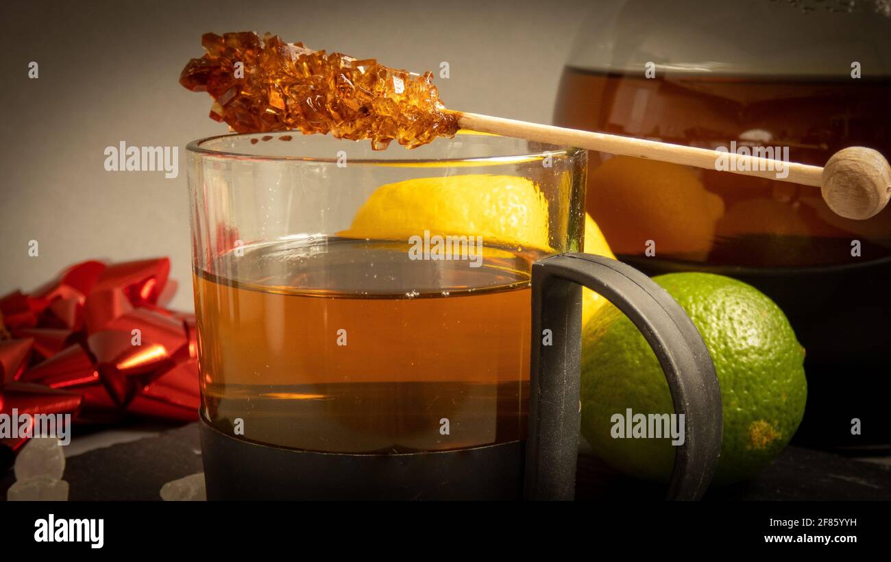 Primo piano di un bicchiere di tè caldo e un limone intero e un lime sul lato Foto Stock