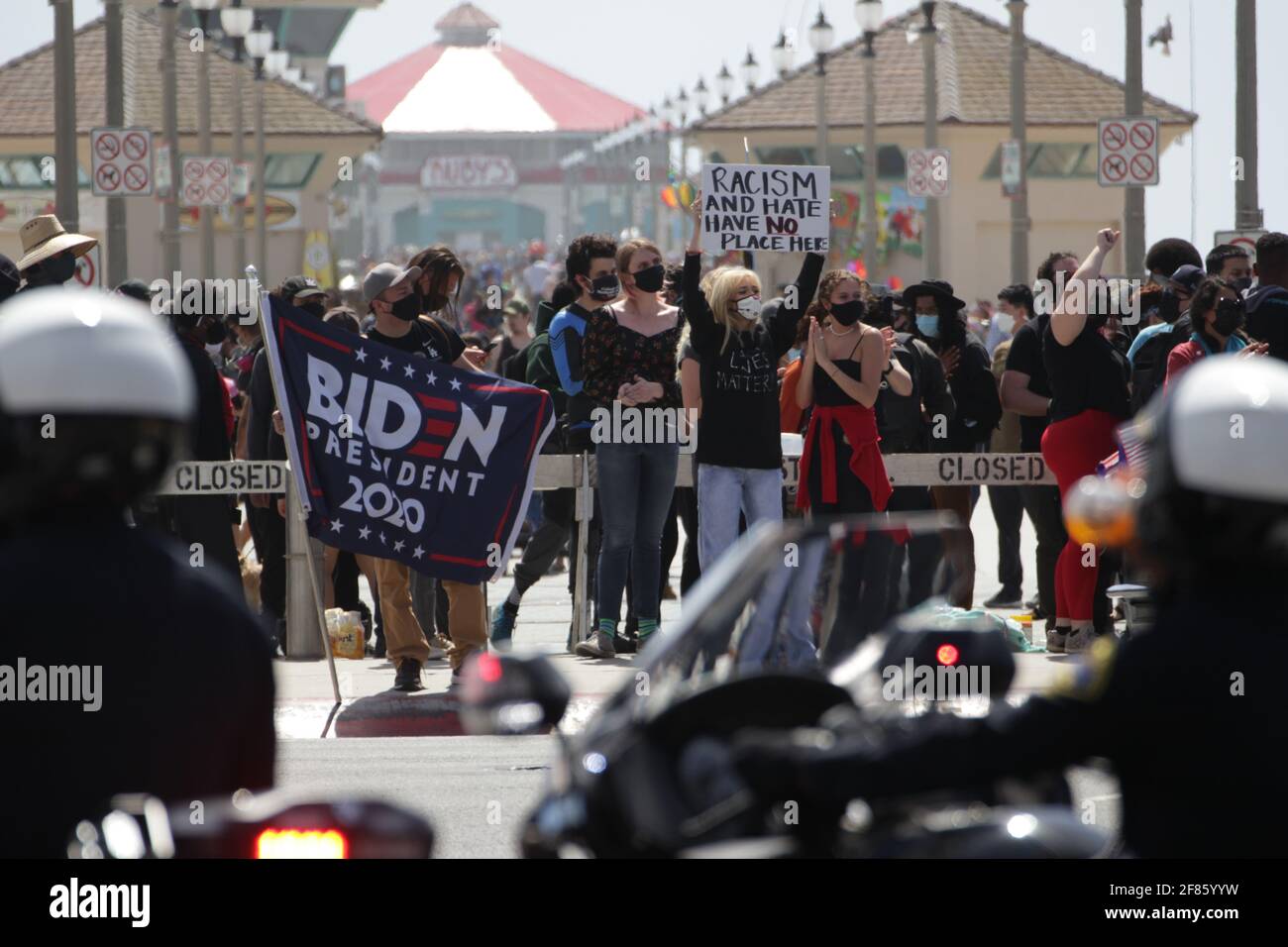 Huntington Beach, California, Stati Uniti. 11 Apr 2021. Gli ufficiali di polizia guardano come una folla di proteste contro un raduno "White Lives Matter" che si è svolto domenica sul molo di Huntington Beach. Credit: Young G. Kim/Alamy Live News Foto Stock