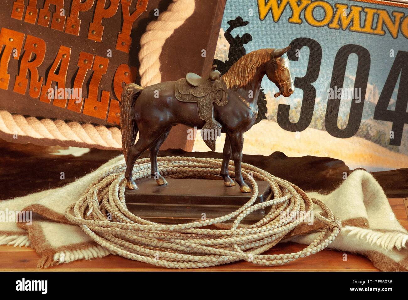 Benvenuto nel Wyoming con il vecchio cavallo saddled, il cavaliere cowboy, la corda, i sentieri e la targa. Vista in primo piano della statua e signs.Composite foto. Foto Stock