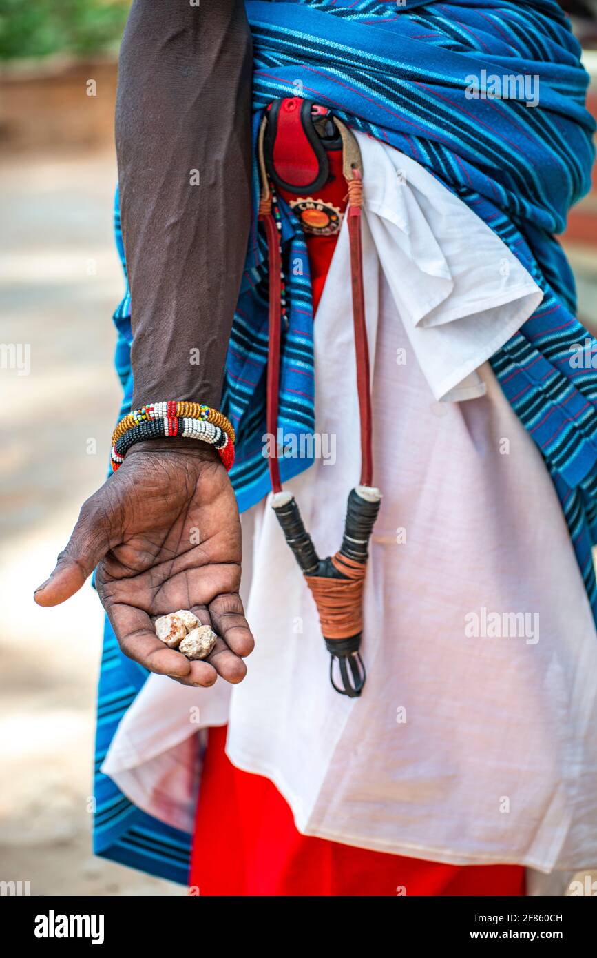 Uomo africano con colpo d'imbragatura e rocce per mantenere la scimmia lontano dai turisti Foto Stock