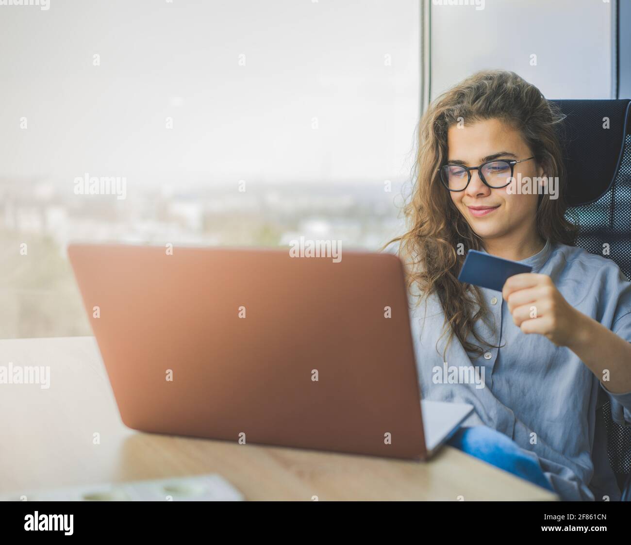 Attraente giovane donna che acquista online con carta di credito Foto Stock