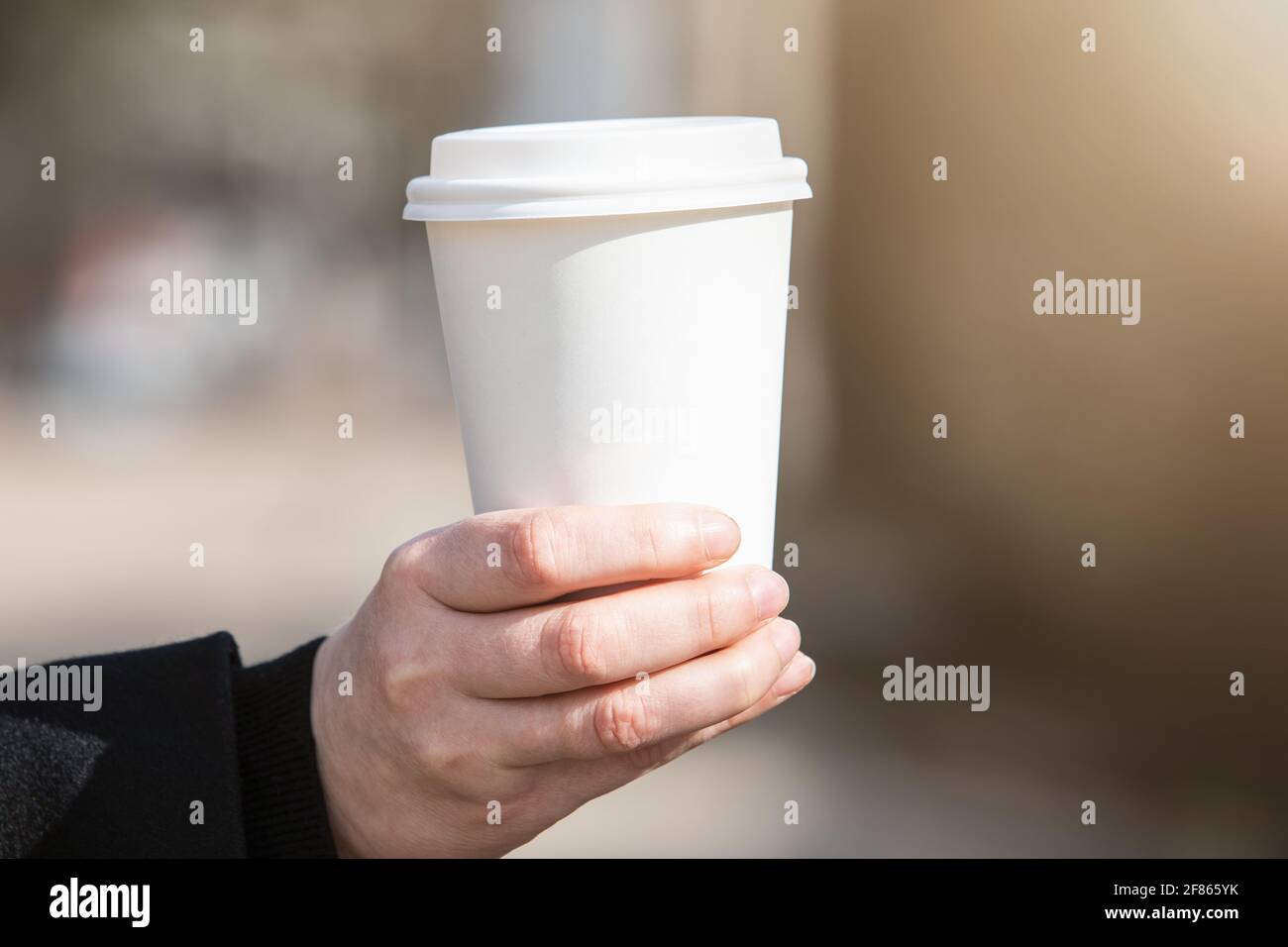 Tazza di carta con caffè in mano della donna. La mattina presto, la colazione e l'inizio del lavoro da. Spazio vuoto per testo, mockup. Foto Stock