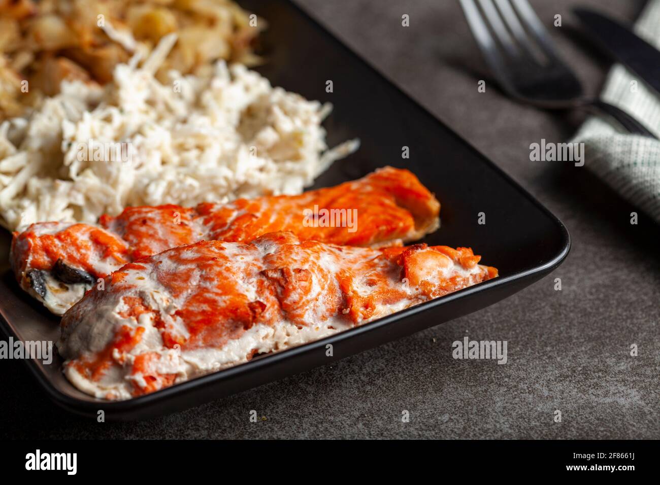 Un servizio di filetti di salmone marinati cotti al forno con insalate di cavolo e sedano per aumentare il contenuto di fibre e vitamine. Una dieta sana ed equilibrata concep Foto Stock