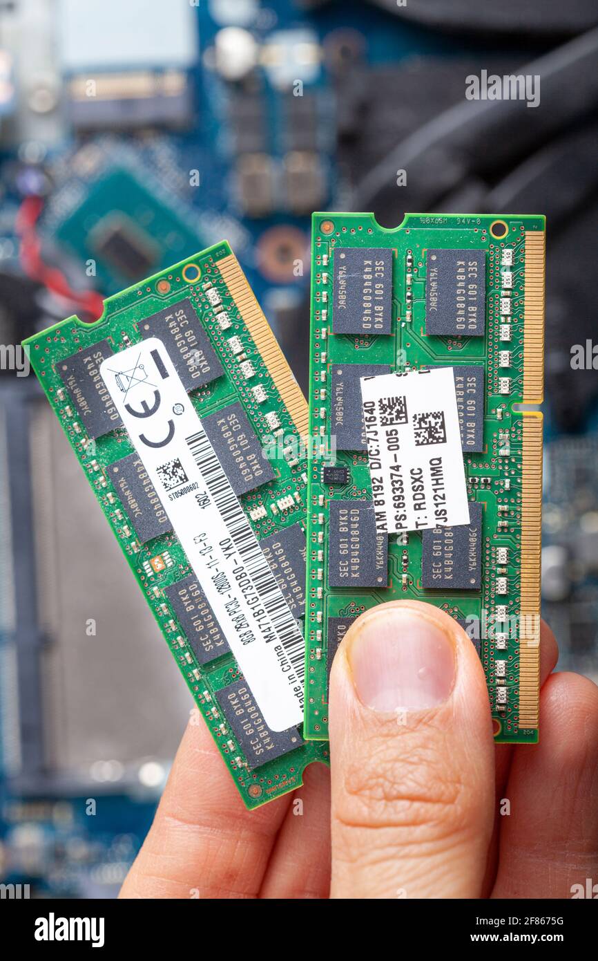 Primo piano immagine isolata che mostra un tecnico IT o un cliente che tiene la scheda RAM in mano con un notebook aperto visto sullo sfondo. Concetto i Foto Stock