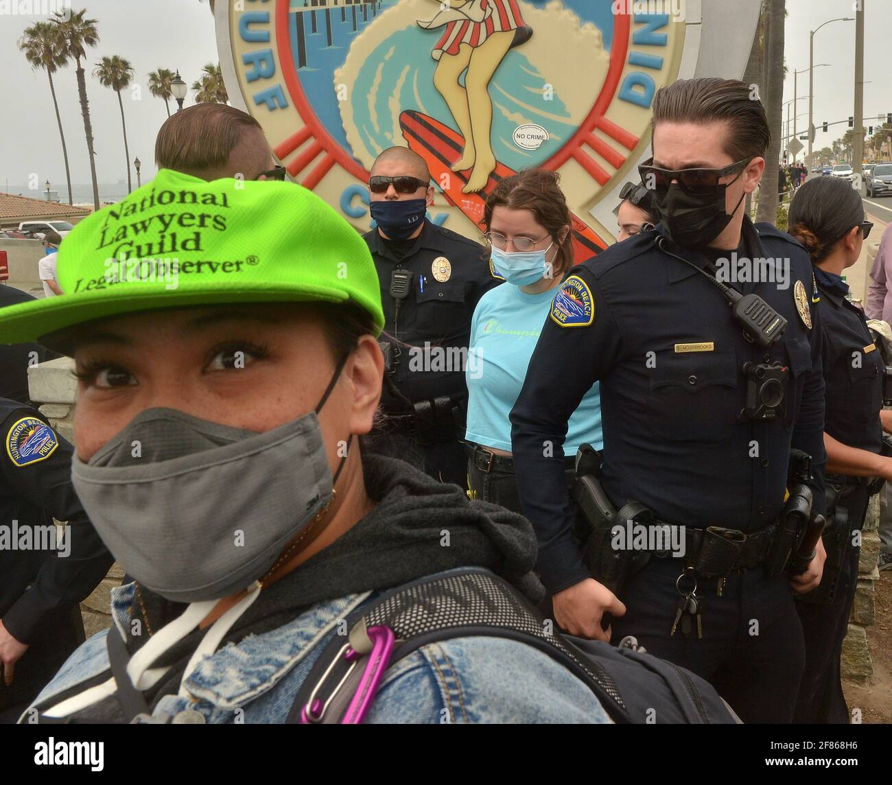 Gli ufficiali di polizia di Huntington Beach arrestano una donna durante una dimostrazione pianificata di White Lives Matter e contrasta la manifestazione Black Lives Matter a Huntington Beach, California, domenica 11 aprile 2021. I manifestanti di BLM hanno occupato Pier Plaza per evitare che il gruppo WLM manifesti la loro presenza. Il raduno della WLM faceva parte di un gruppo nazionale di proteste programmate in una manciata di città in tutto il paese per combattere ciò che gli organizzatori vedono come la minaccia alla corsa bianca dal multiculturalismo e ciò che essi hanno denominato come il bias 'anti-bianco' nei media, nel governo e nell'istruzione. Foto di Jim Ruymen/UPI Foto Stock