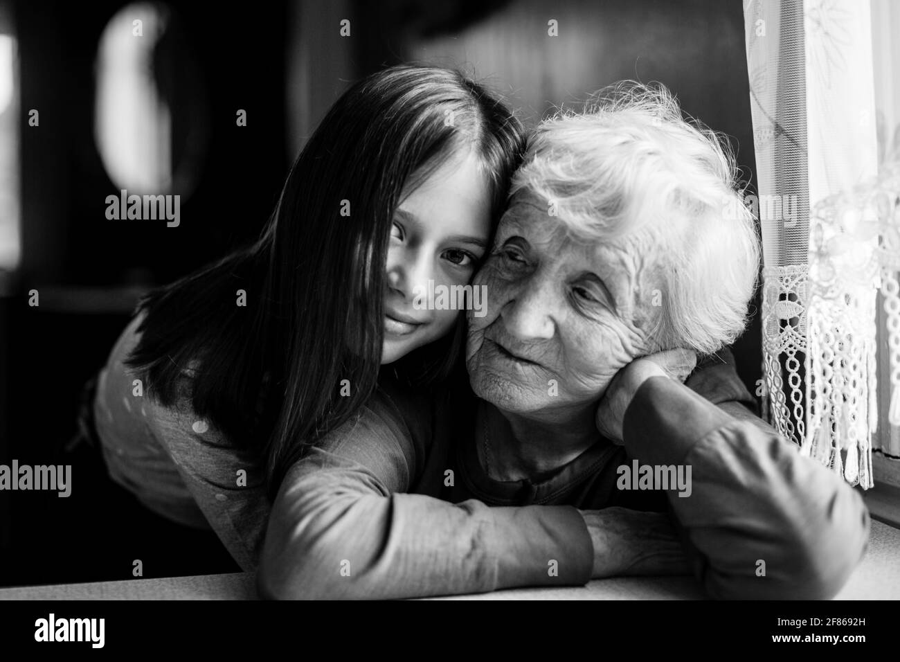 La bambina abbraccia la sua vecchia nonna. Foto in bianco e nero. Foto Stock