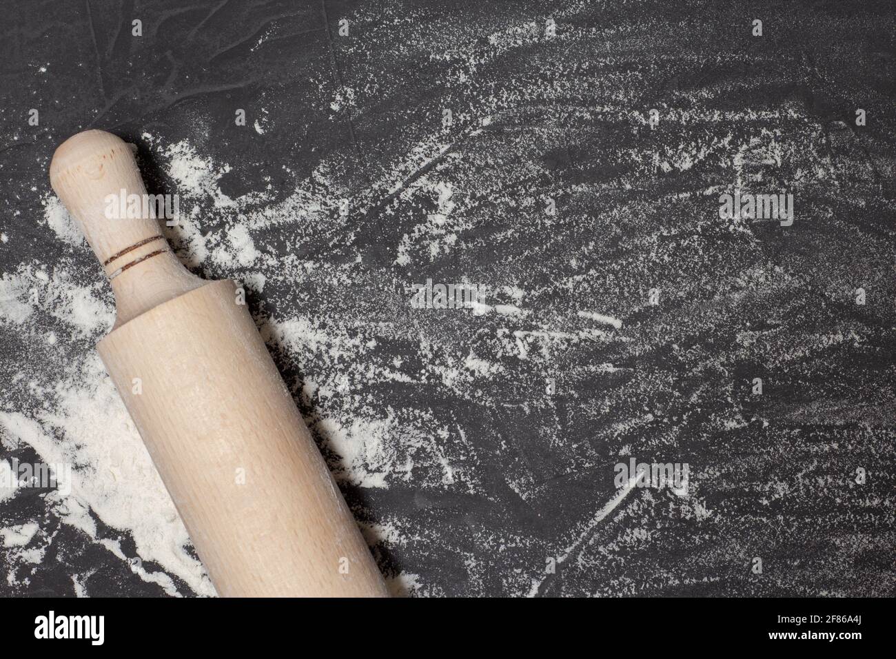 Tondino e farina bianca su tavola di pietra nera. Banner per il web con spazio libero per il tuo testo. Concept per panetteria. Vista dall'alto, spazio di copia Foto Stock