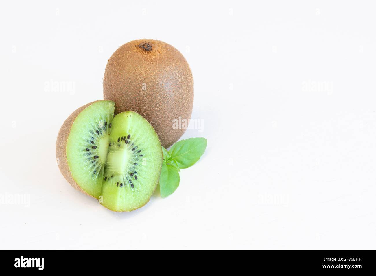 Frutti di kiwi interi e metà isolati su sfondo bianco con spazio di testo Foto Stock