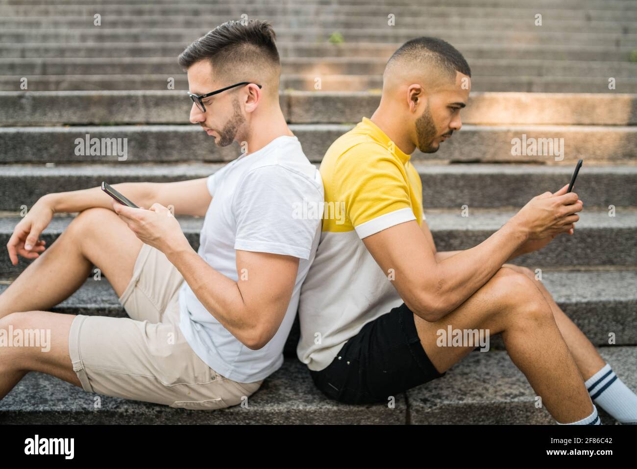 Una coppia gay si ignora mentre usa il telefono. Foto Stock