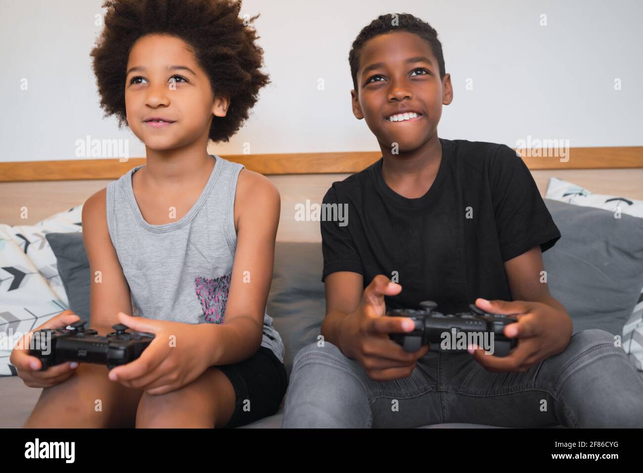 Due fratelli che giocano a videogame a casa. Foto Stock