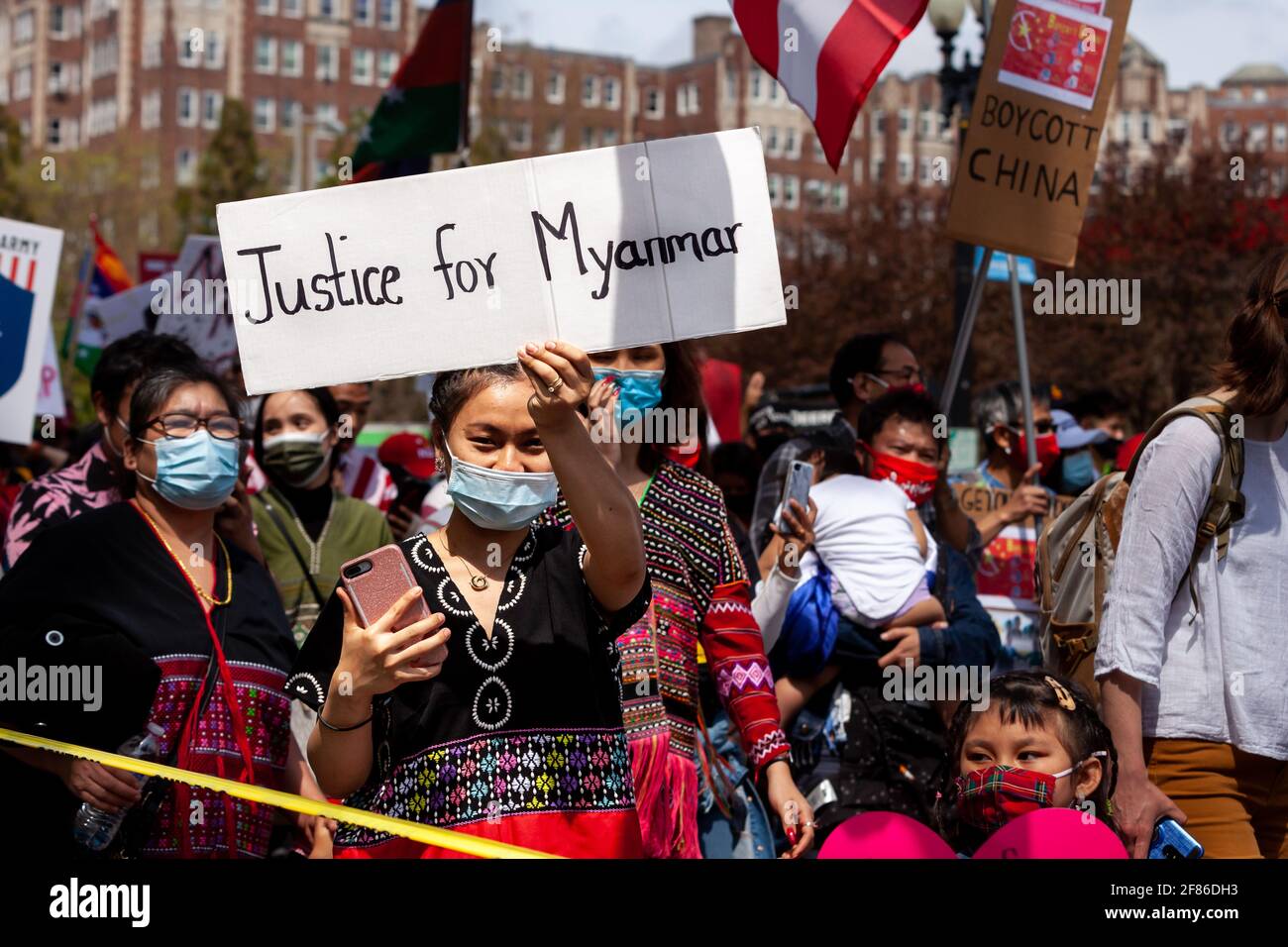 Un manifestante in abito tradizionale ha un segno che chiede giustizia durante una marcia contro il colpo di stato militare in Myanmar. Foto Stock