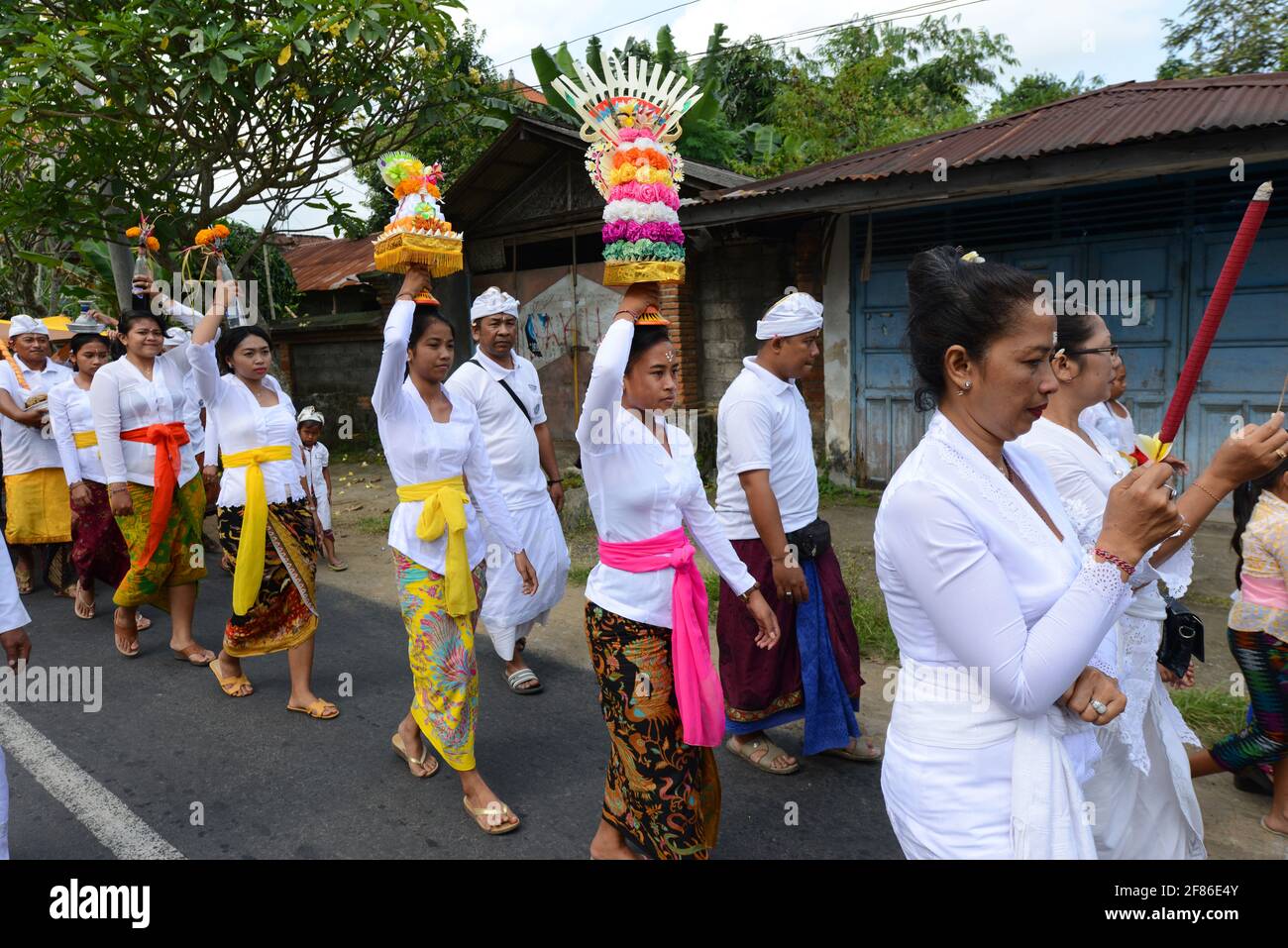 Processione di donne tradizionalmente vestite che portano offerte di templi / gebogani sulla loro testa vicino a Ubud, Bali, Indonesia. Foto Stock