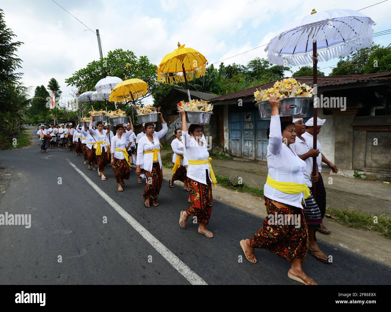 Processione di donne tradizionalmente vestite che portano offerte di templi / gebogani sulla loro testa vicino a Ubud, Bali, Indonesia. Foto Stock