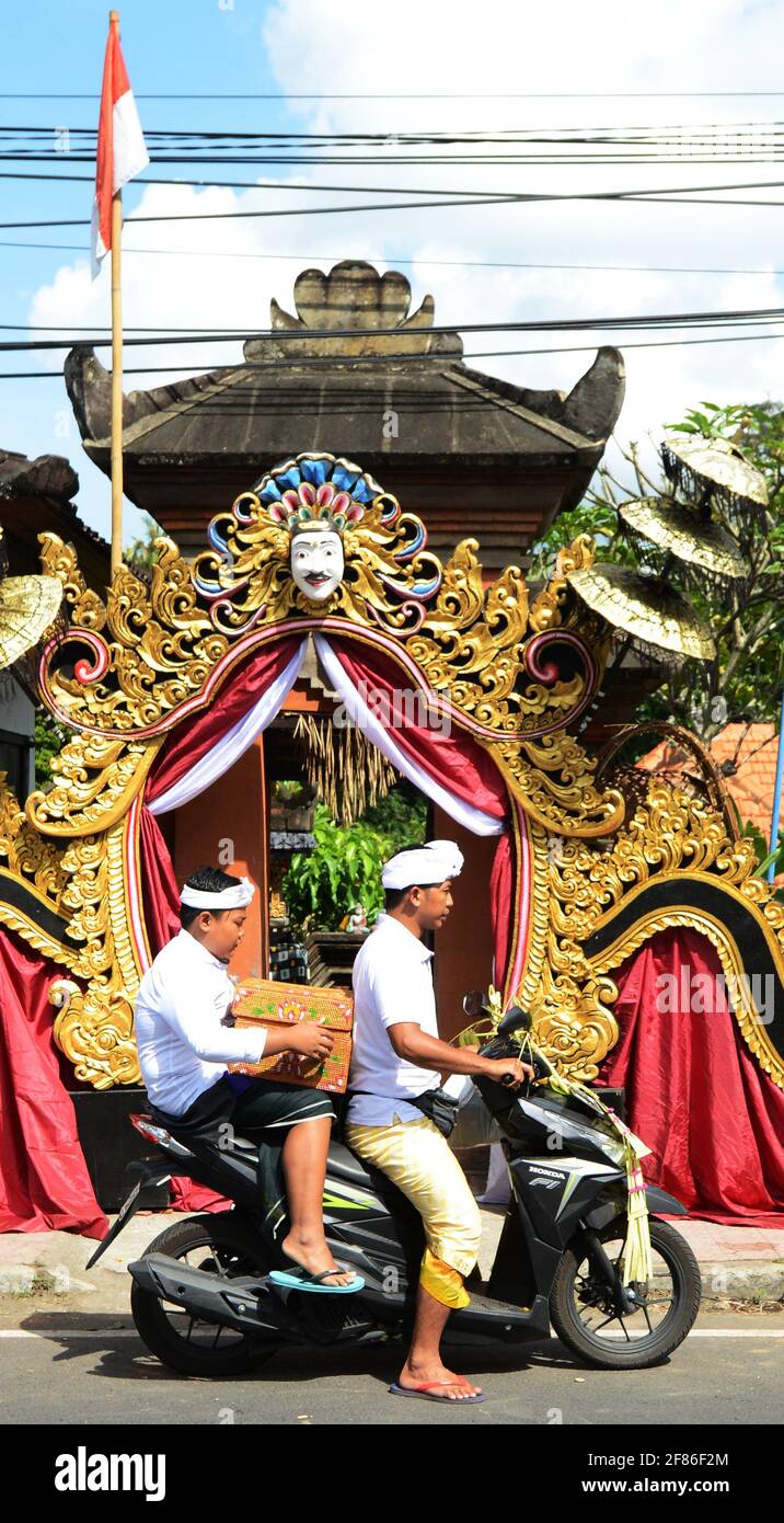 Padre e figlio balinese che prendono offerte di tempio su scooter therioter. Foto Stock