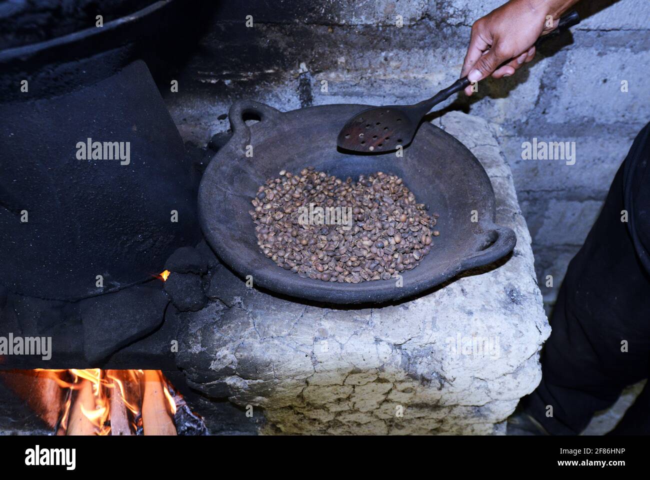 Un uomo balinese arrostire i chicchi di caffè. Foto Stock