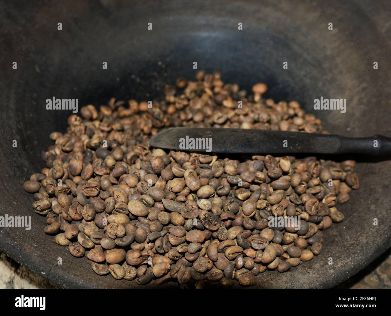 Un uomo balinese arrostire i chicchi di caffè. Foto Stock