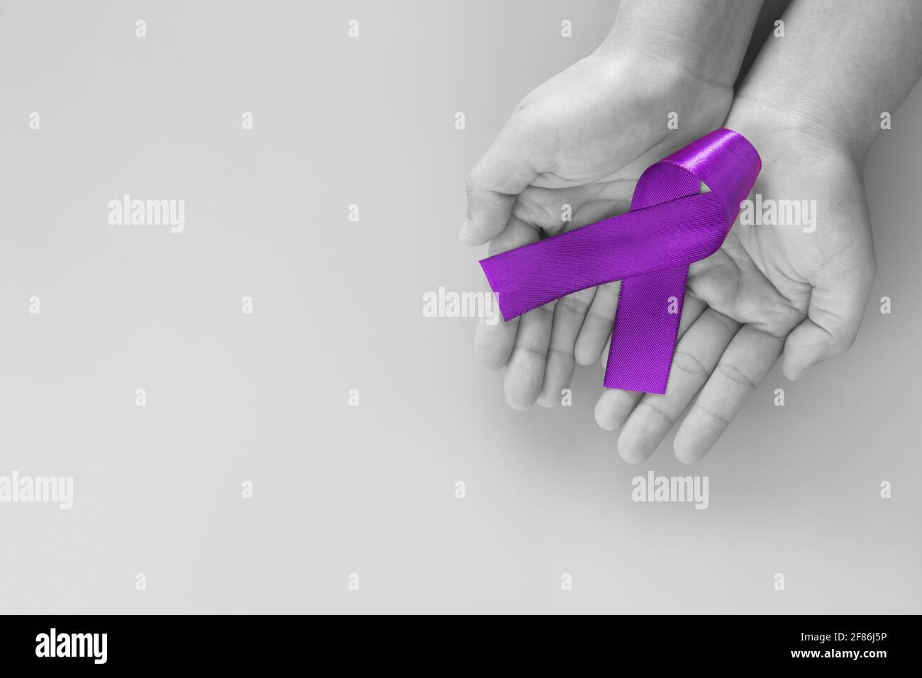 Mani che tengono il nastro viola o viola su sfondo viola con spazio per la copia. Cancro pancreatico consapevolezza del cancro testicolare cancro Survivor Leiomyosarco Foto Stock