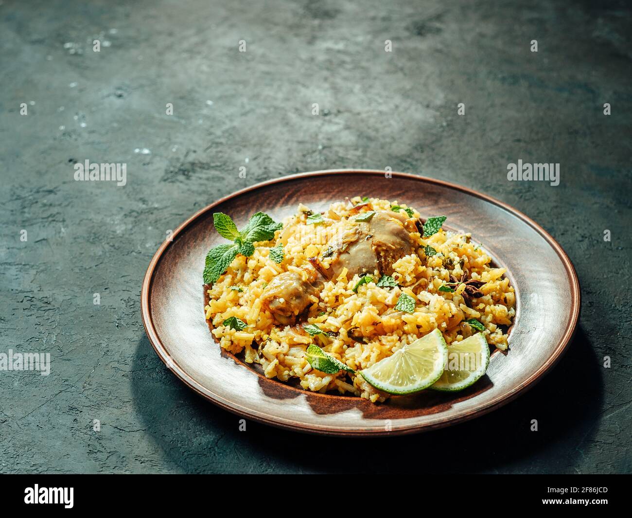 Cibo pakistano - riso biryano con pollo sul piatto. Delizioso pollo biryani hyberabadi su sfondo scuro. Spazio di copia per testo o disegno Foto Stock