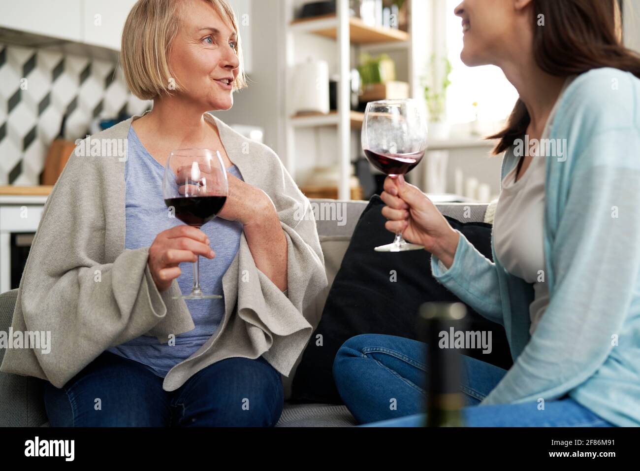 Donne di due generazioni che bevono vino a casa Foto Stock