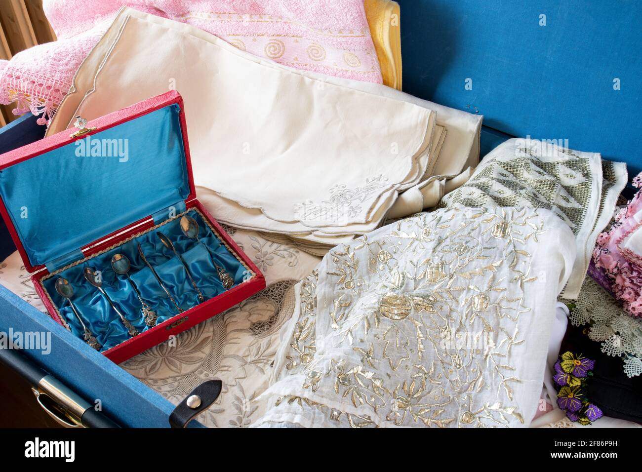 Dote in stile turco in un petto di dote blu, antichi cucchiai, piatti, asciugamani ricamati, mussola ricamata e pizzo. Braccio di messa a fuoco selettiva Foto Stock