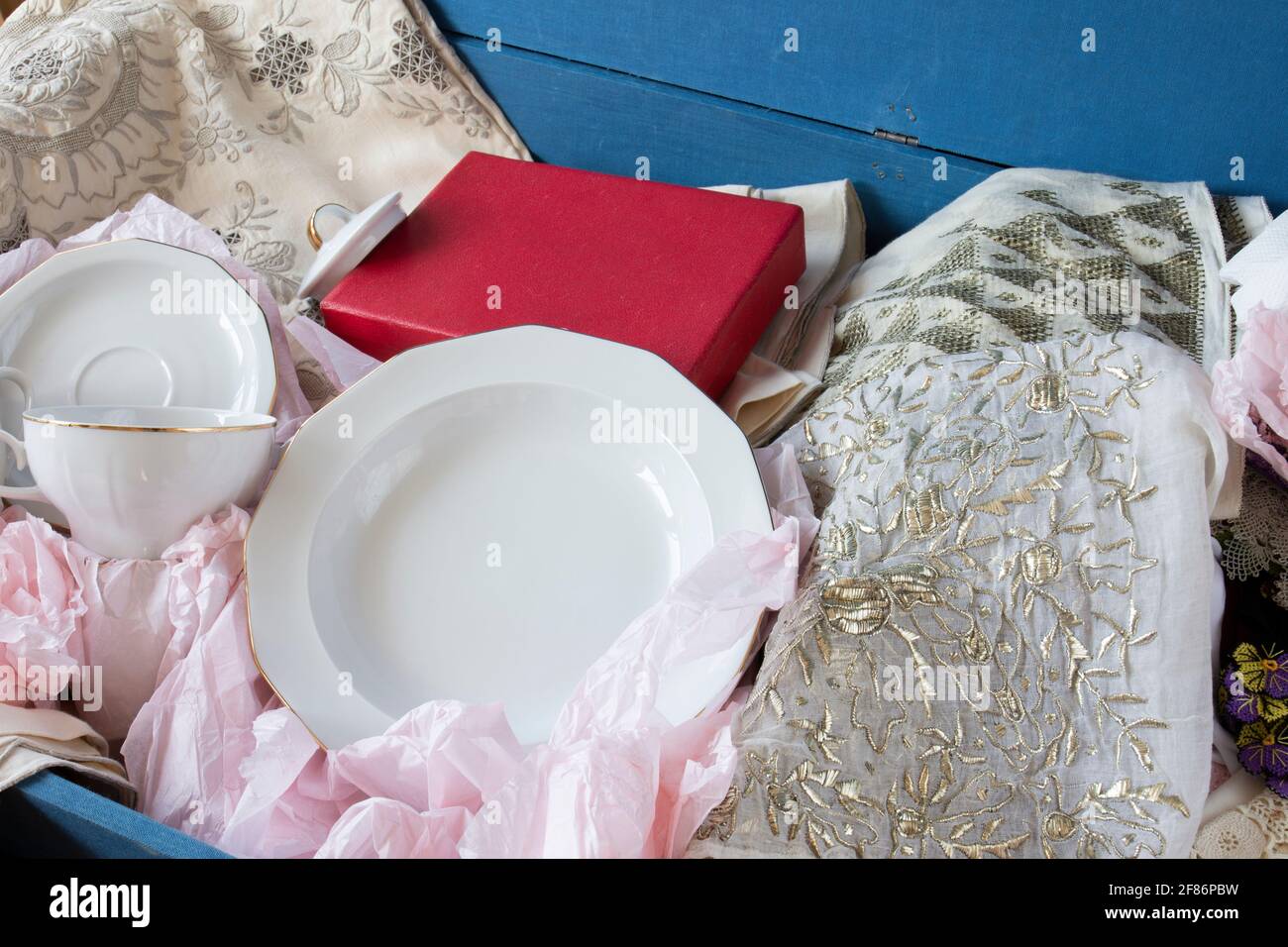 Dote in stile turco in un petto di dote blu, antichi cucchiai, piatti, asciugamani ricamati, mussola ricamata e pizzo. Braccio di messa a fuoco selettiva Foto Stock
