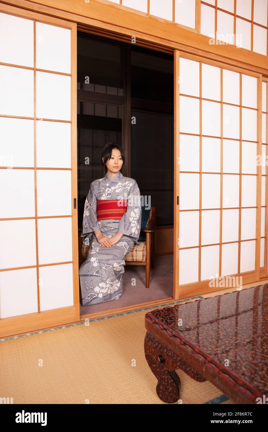 Serena giovane donna giapponese in kimono alla porta shoji Foto Stock