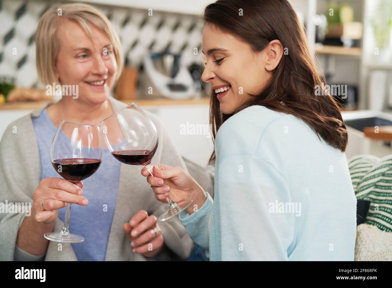Felice figlia adulta e madre anziana tostatura in vino Foto Stock