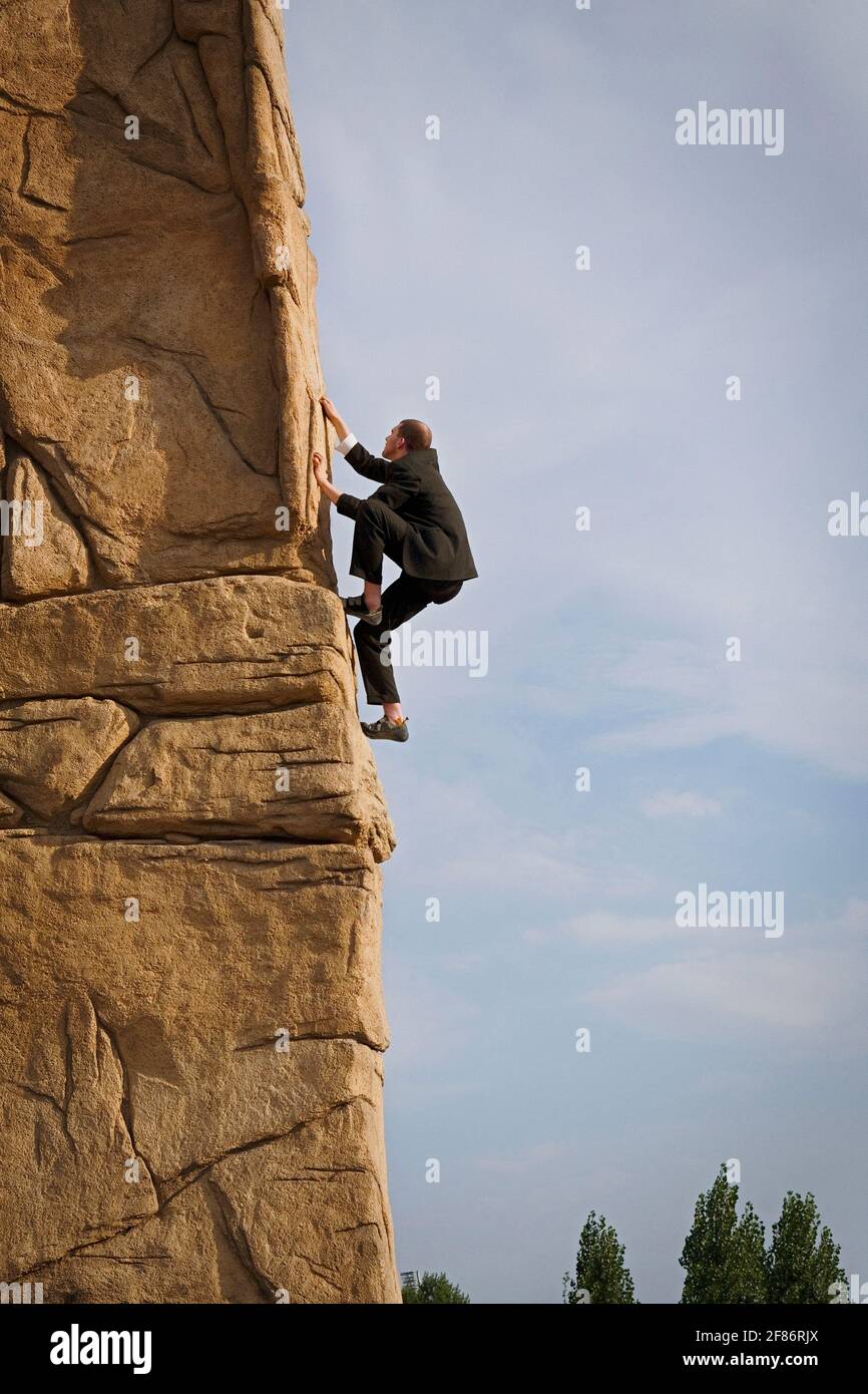 Uomo d'affari arrampicata ripida parete di roccia Foto Stock
