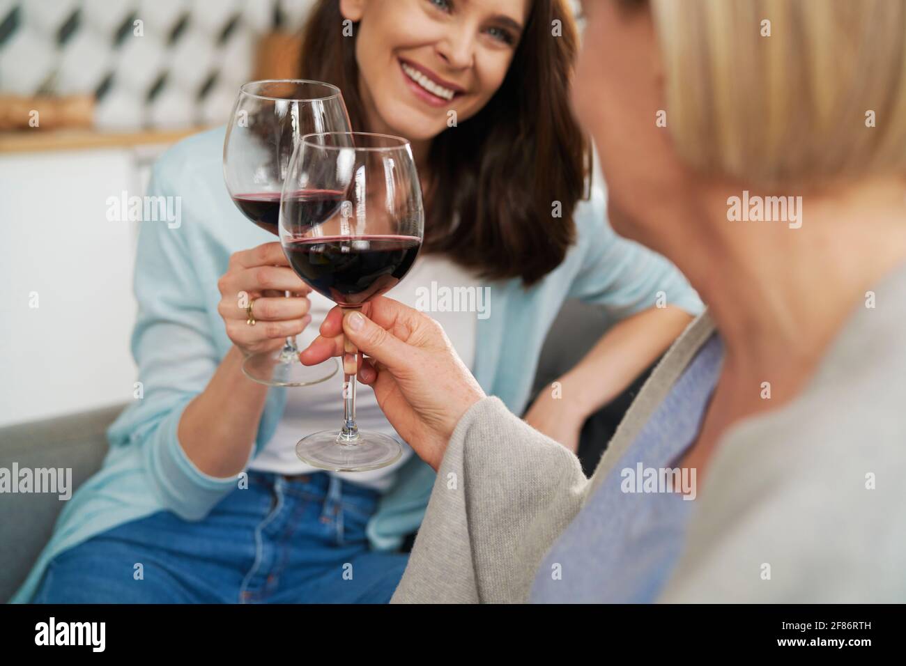 Primo piano di madre e figlia adulta che tostano nel vino Foto Stock