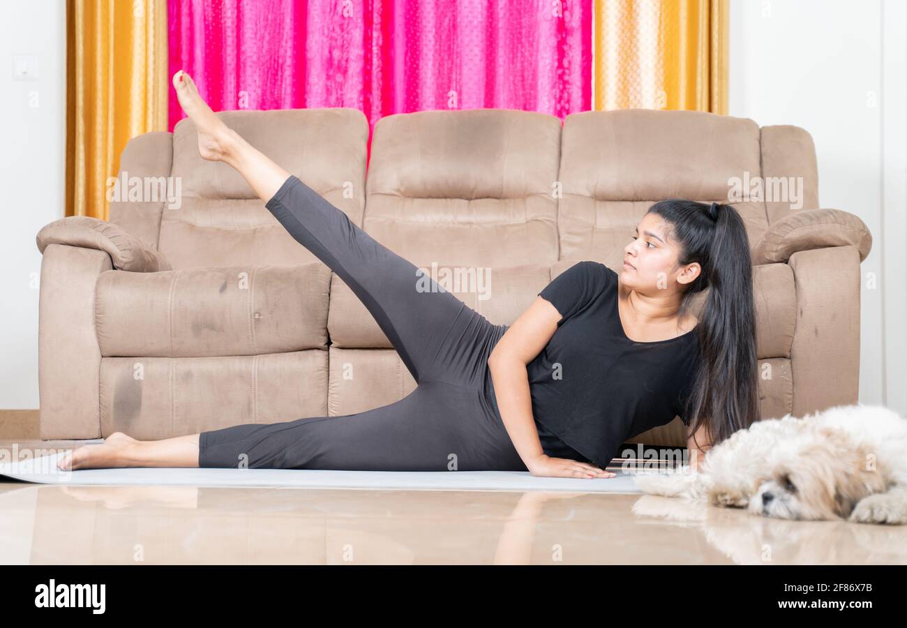 La ragazza giovane con il suo animale domestico da parte facendo l'esercitazione sul tappeto di yoga nel paese - concetto di nuovo lifetyle sano normale dovuto la pandemic del covid-19 del coronavirus. Foto Stock