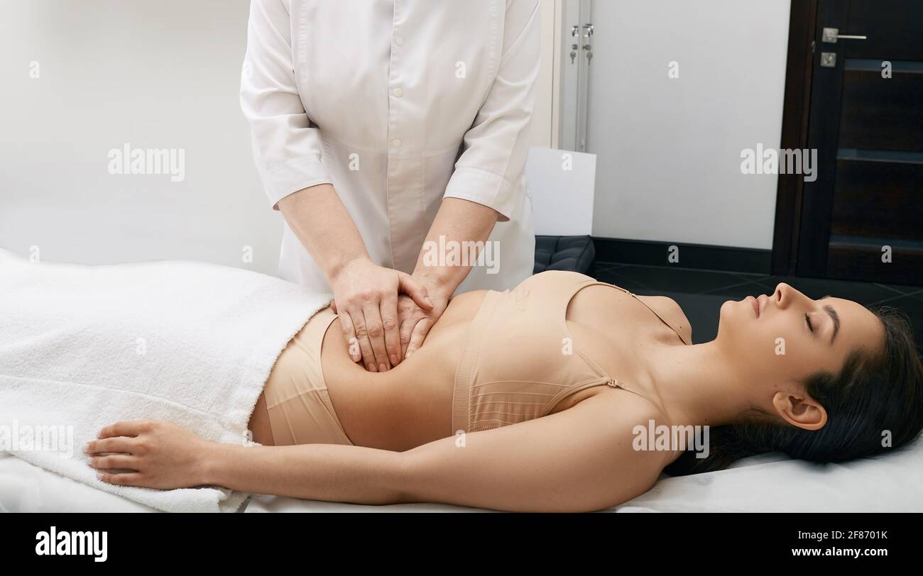 il medico palpa la pancia di una giovane donna in una clinica medica. Medico che fa un esame medico per il corpo femminile per la prevenzione delle malattie Foto Stock