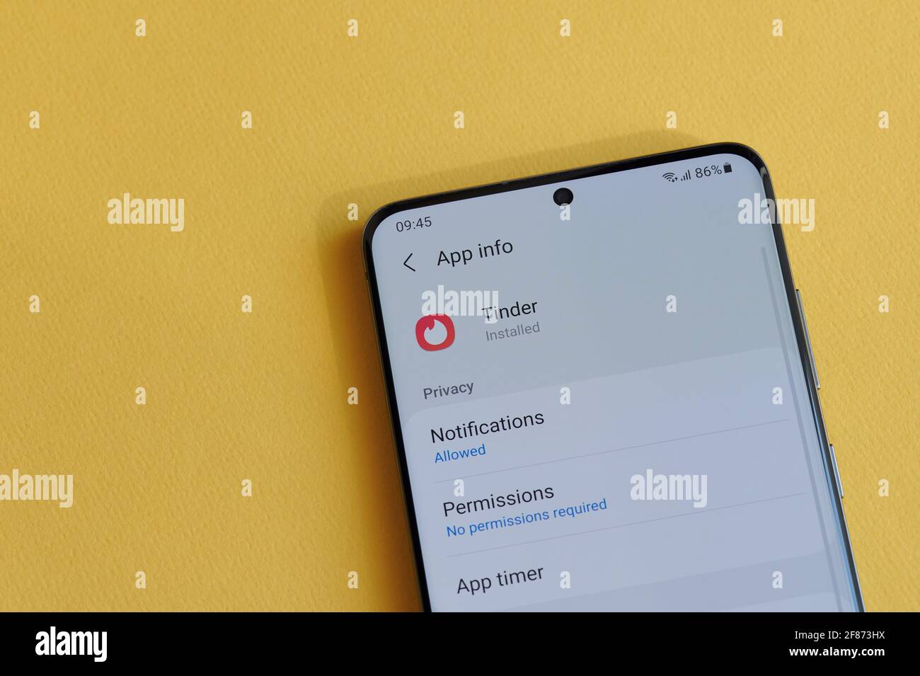 New york, USA - 12 aprile 2021: Modifica dell'impostazione della privacy nell'app Tinder sullo schermo dello smartphone su sfondo giallo Foto Stock