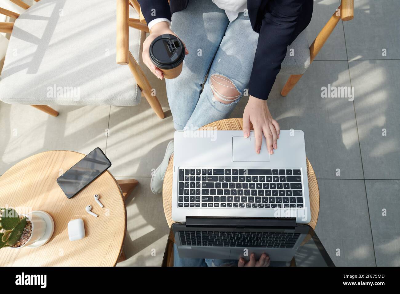 Mani di una studentessa universitaria che beve caffè e lavora su un computer portatile, studia e lavora su un progetto, vista dall'alto Foto Stock